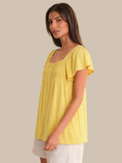Woman wearing a yellow top against a beige background