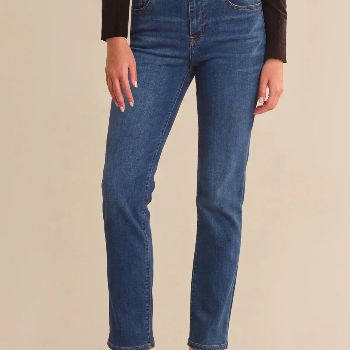 Person wearing blue jeans with a beige background