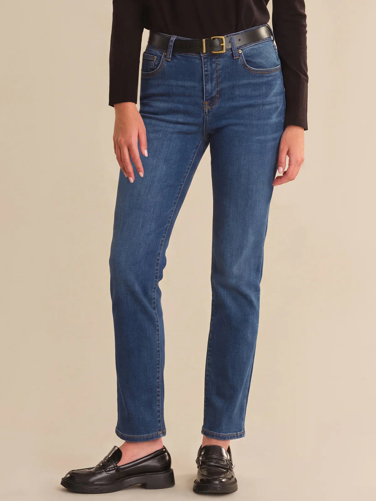 Person wearing blue jeans with a beige background