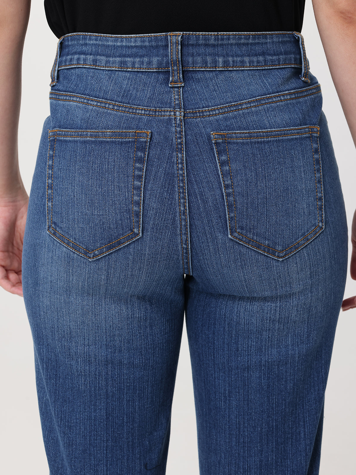 Blue jeans worn by a person on a plain background