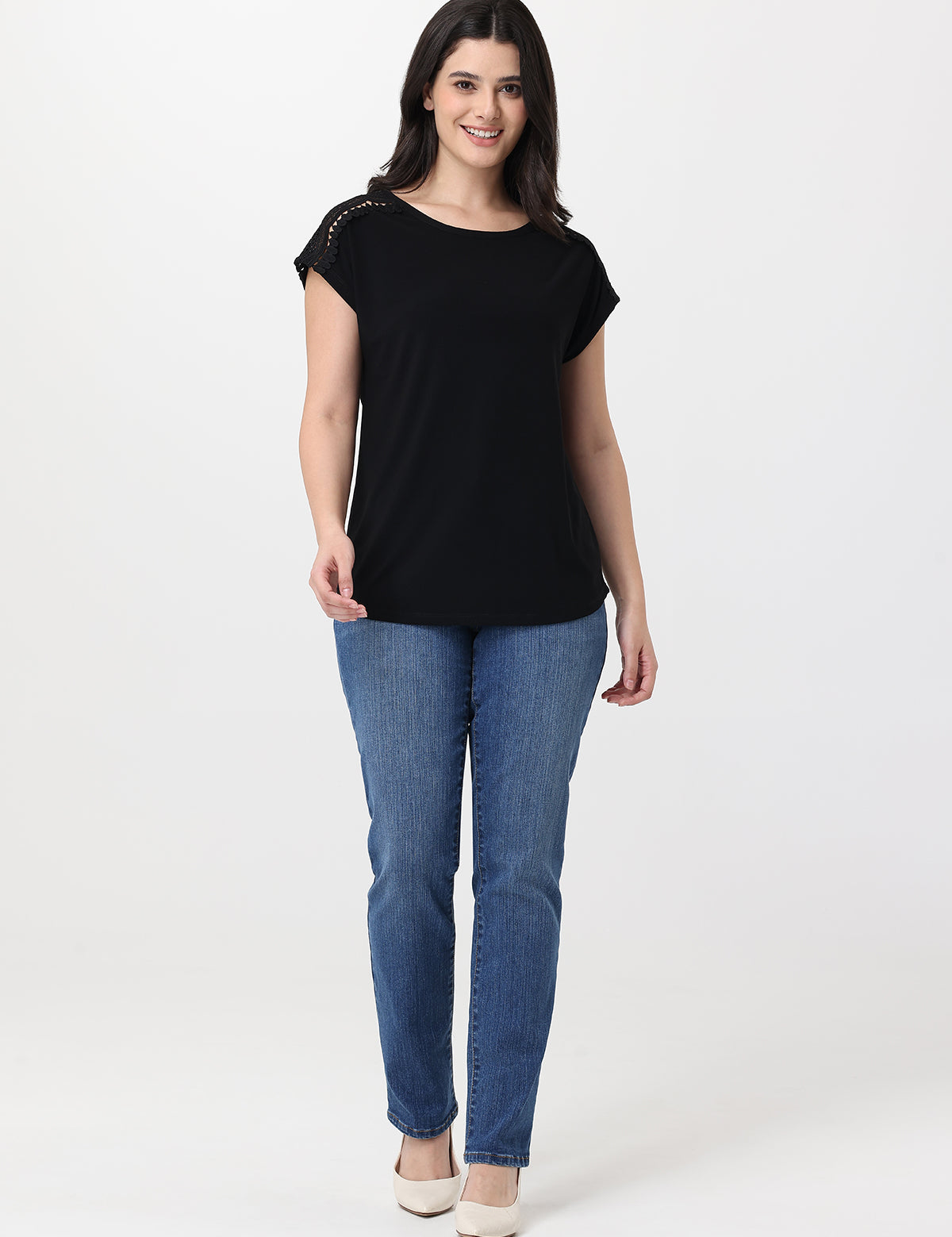 Woman wearing a black top and blue jeans on a white background