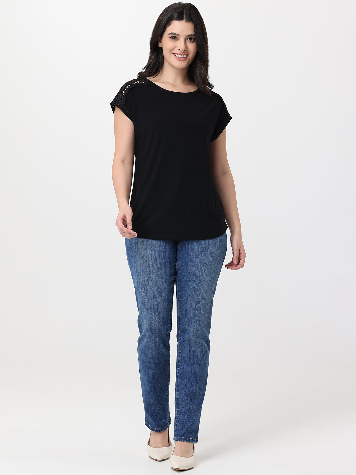 Woman wearing a black top and blue jeans on a white background