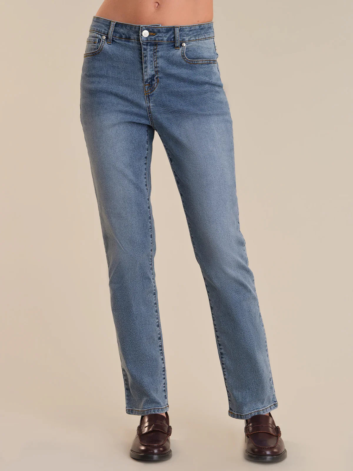 Blue jeans worn by a person on a beige background
