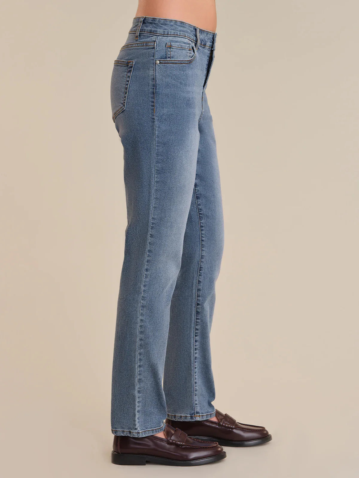 Blue jeans worn by a person on a beige background