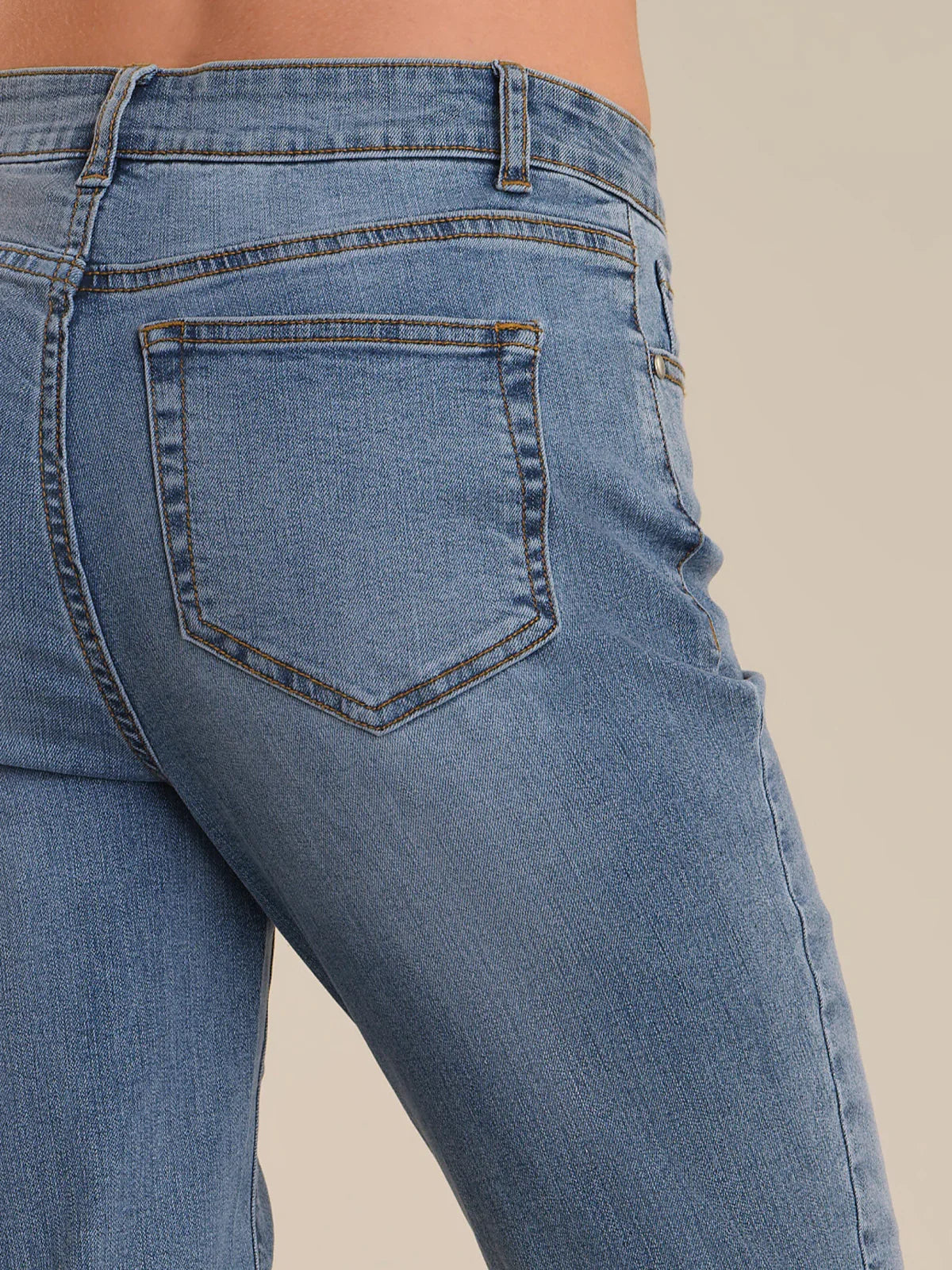 Close-up of blue jeans with a beige background