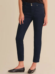 Person wearing dark blue jeans on a beige background