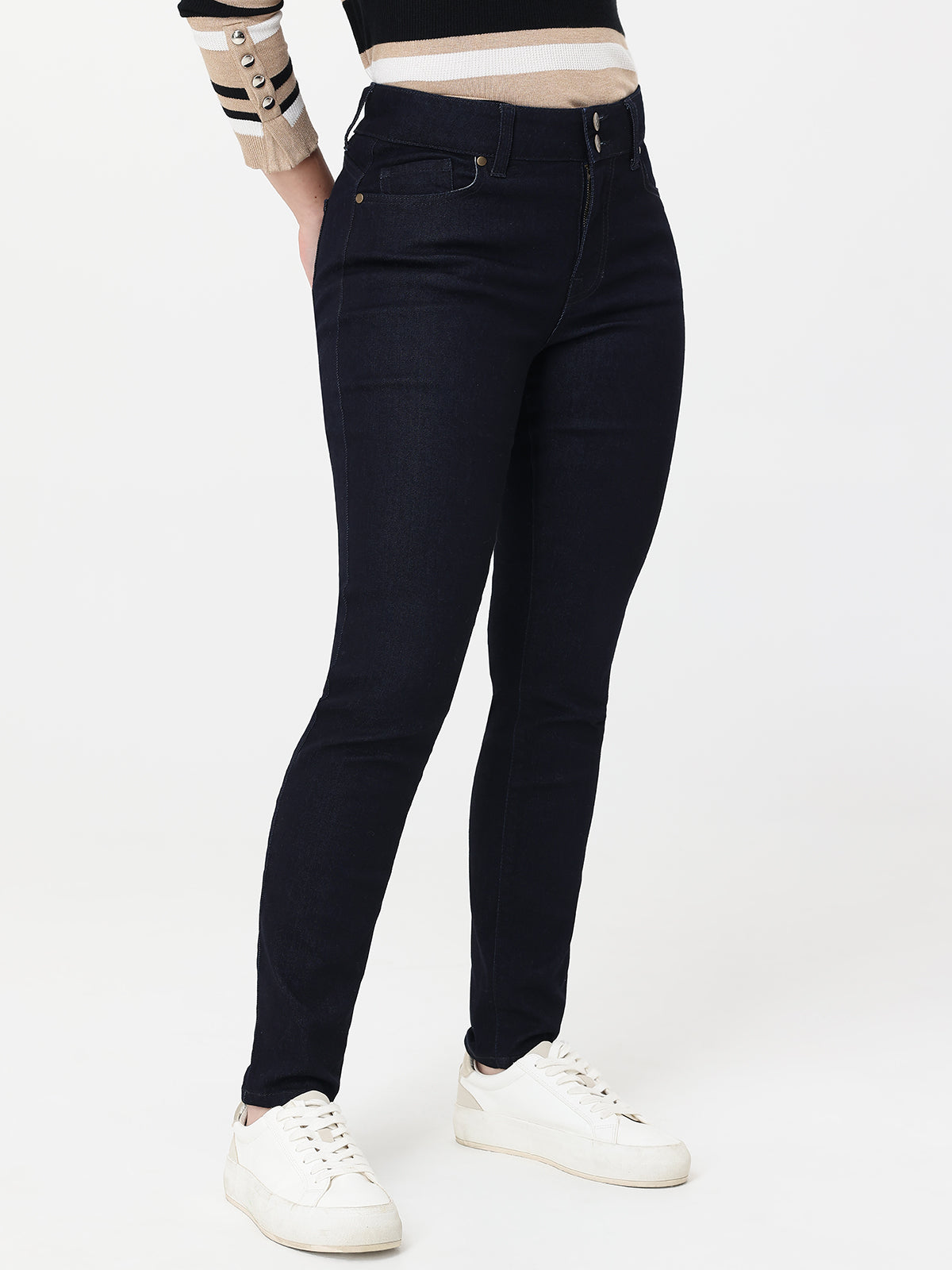 Person wearing navy blue jeans and white sneakers on a white background