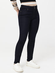 Person wearing navy blue jeans and white sneakers on a white background