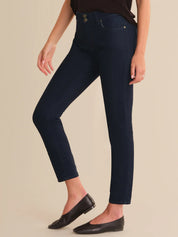 Person wearing dark blue jeans and black shoes on a beige background