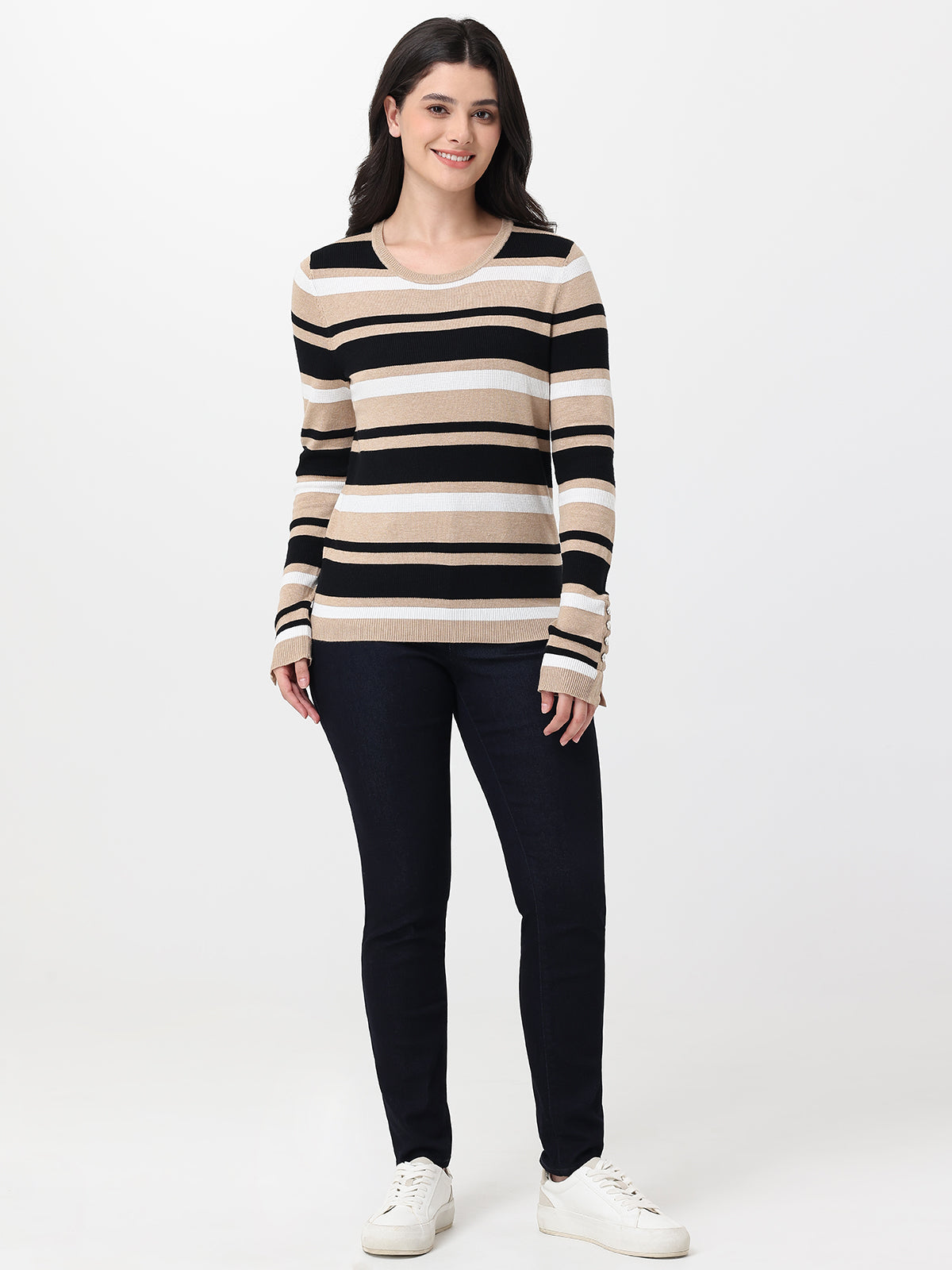 Woman wearing a striped sweater and navy jeans on a white background