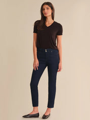 Woman wearing a black t-shirt and navy jeans on a beige background