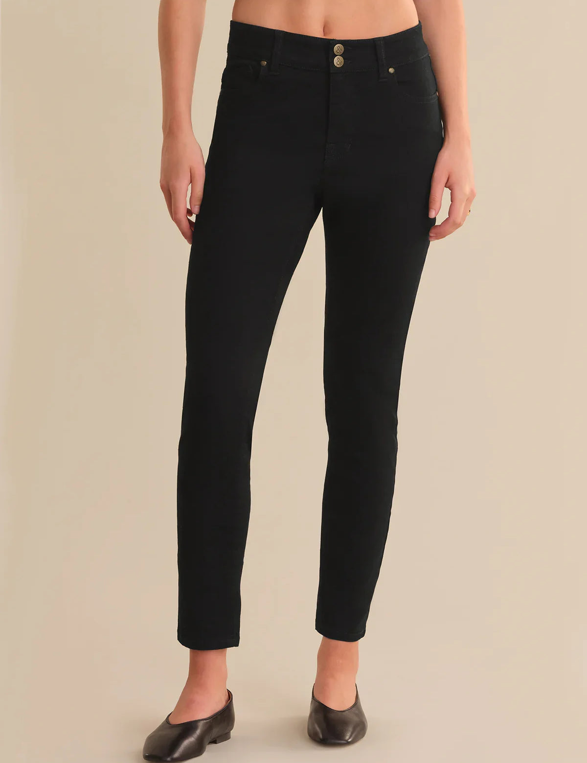 Person wearing black jeans on a beige background