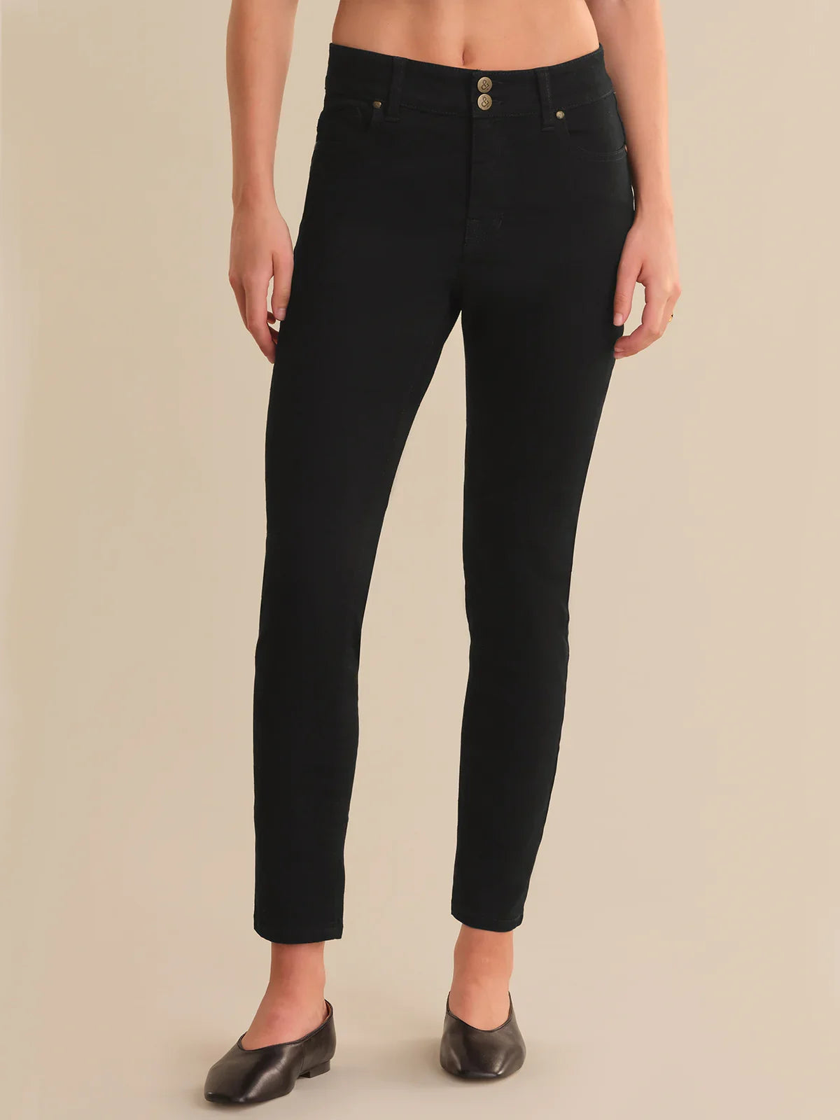 Person wearing black jeans on a beige background