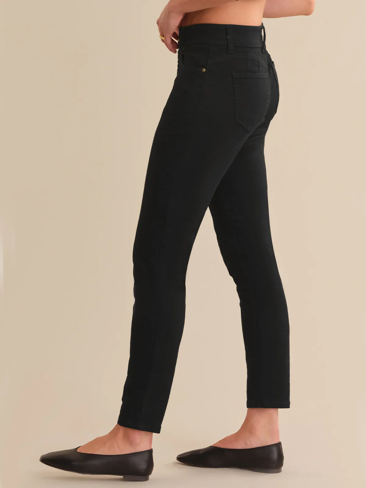 Black jeans worn by a person on a beige background