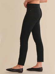 Black jeans worn by a person on a beige background