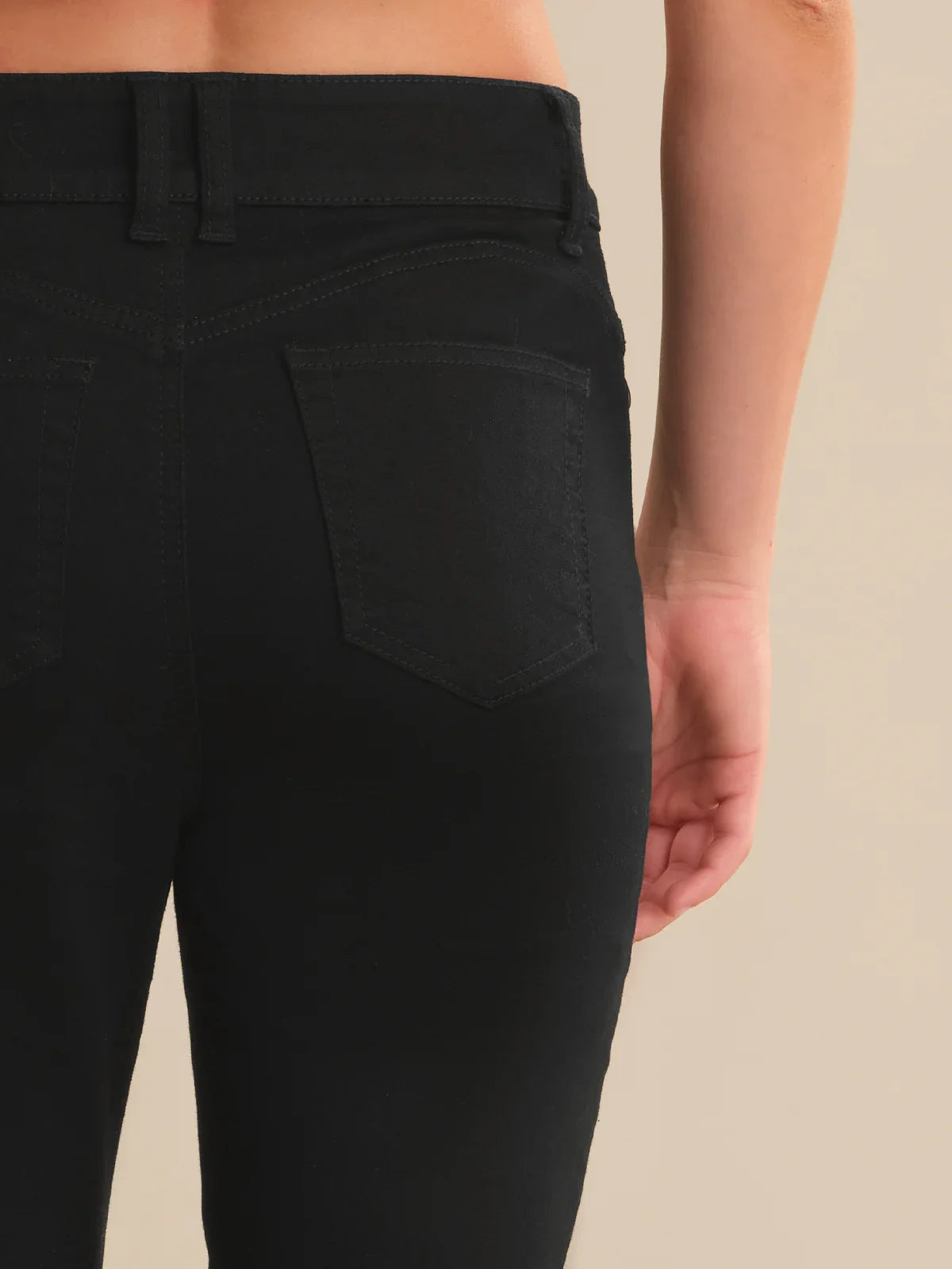 Black pants worn by a person on a beige background