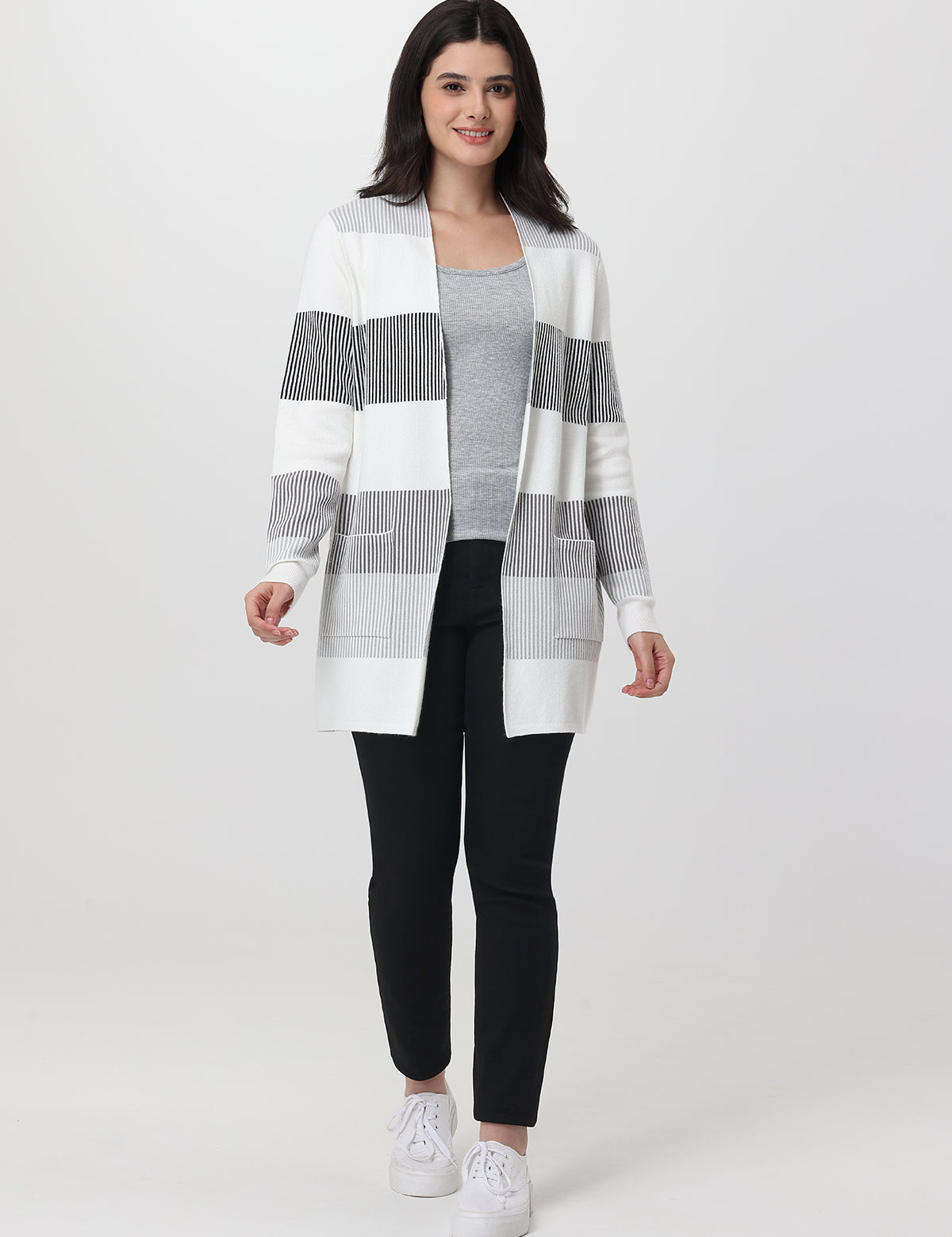 Woman wearing a black jeans and white striped cardigan on a white background