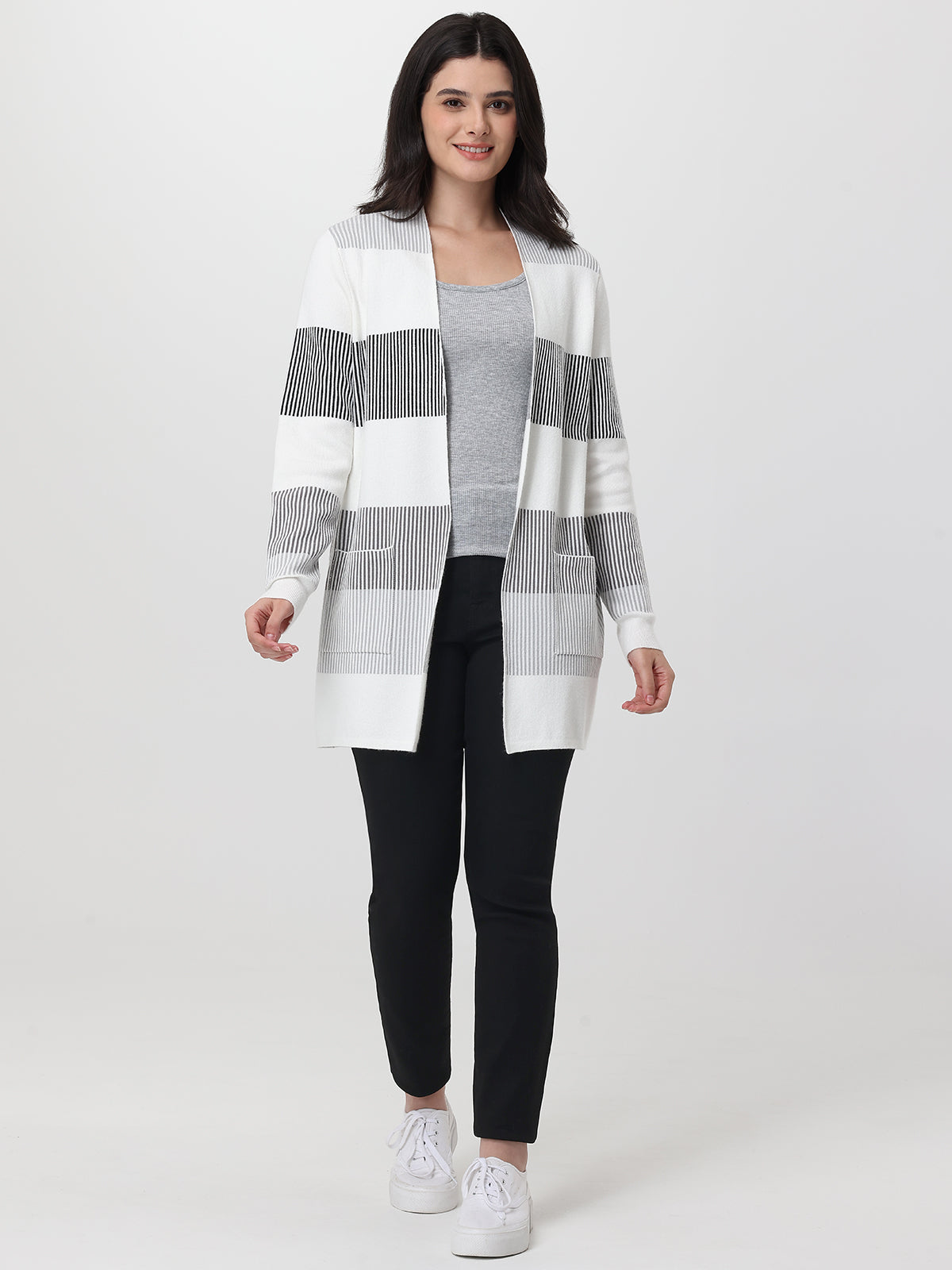 Woman wearing a black jeans and white striped cardigan on a white background