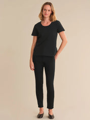 Woman wearing a black t-shirt and black pants on a beige background