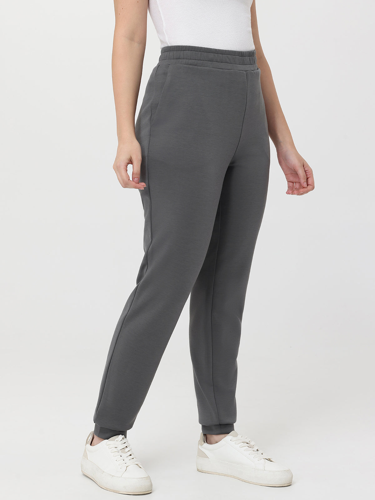 Person wearing gray pants and white sneakers on a white background