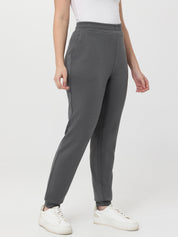 Person wearing gray pants and white sneakers on a white background