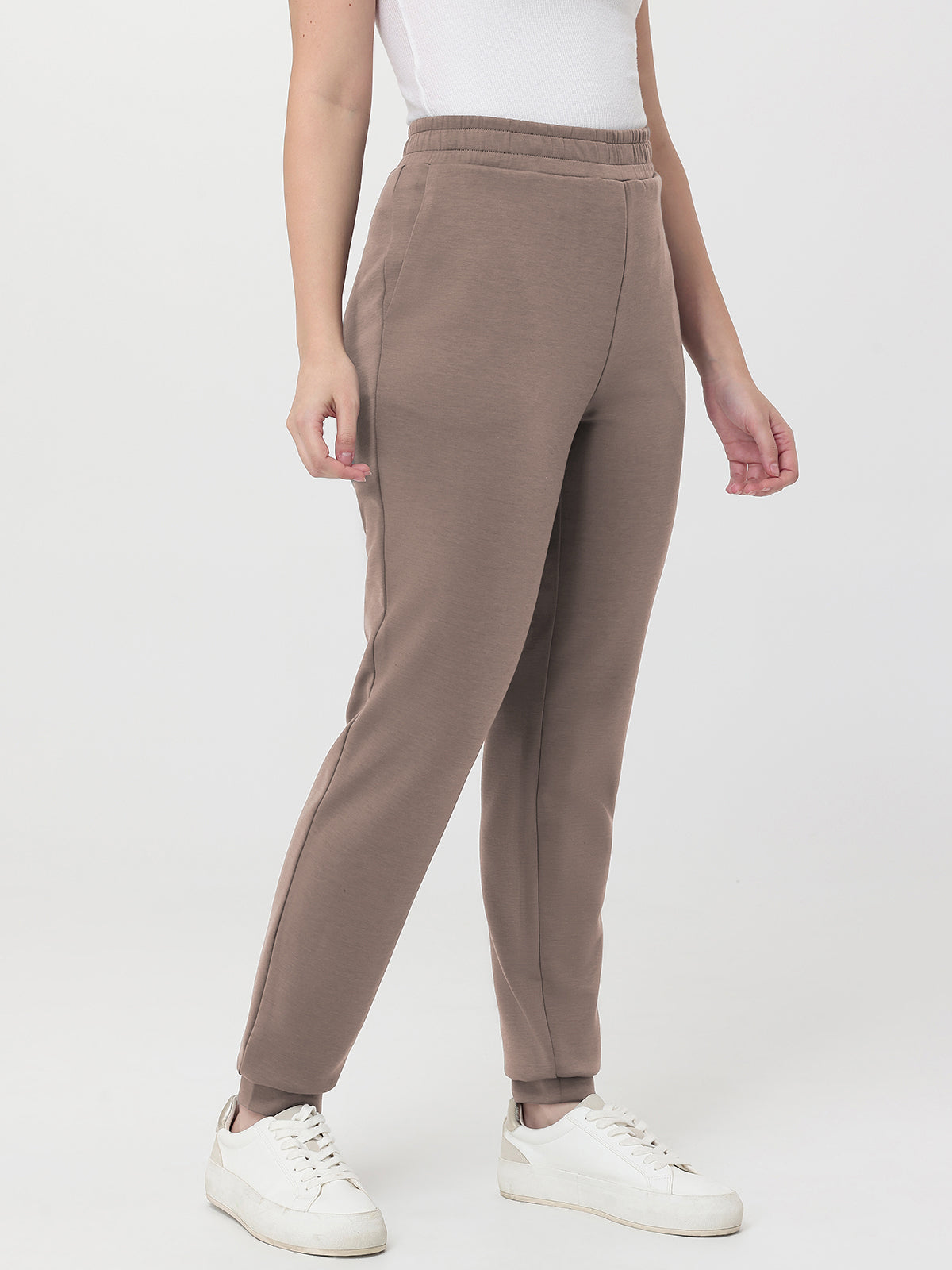 Person wearing brown pants and white sneakers on a white background