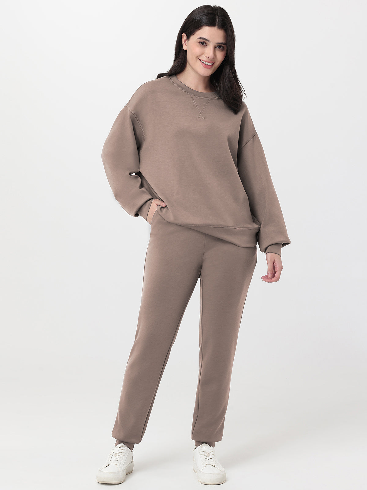 Woman wearing a brown sweatshirt and pants set on a white background