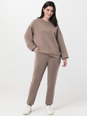 Woman wearing a brown sweatshirt and pants set on a white background