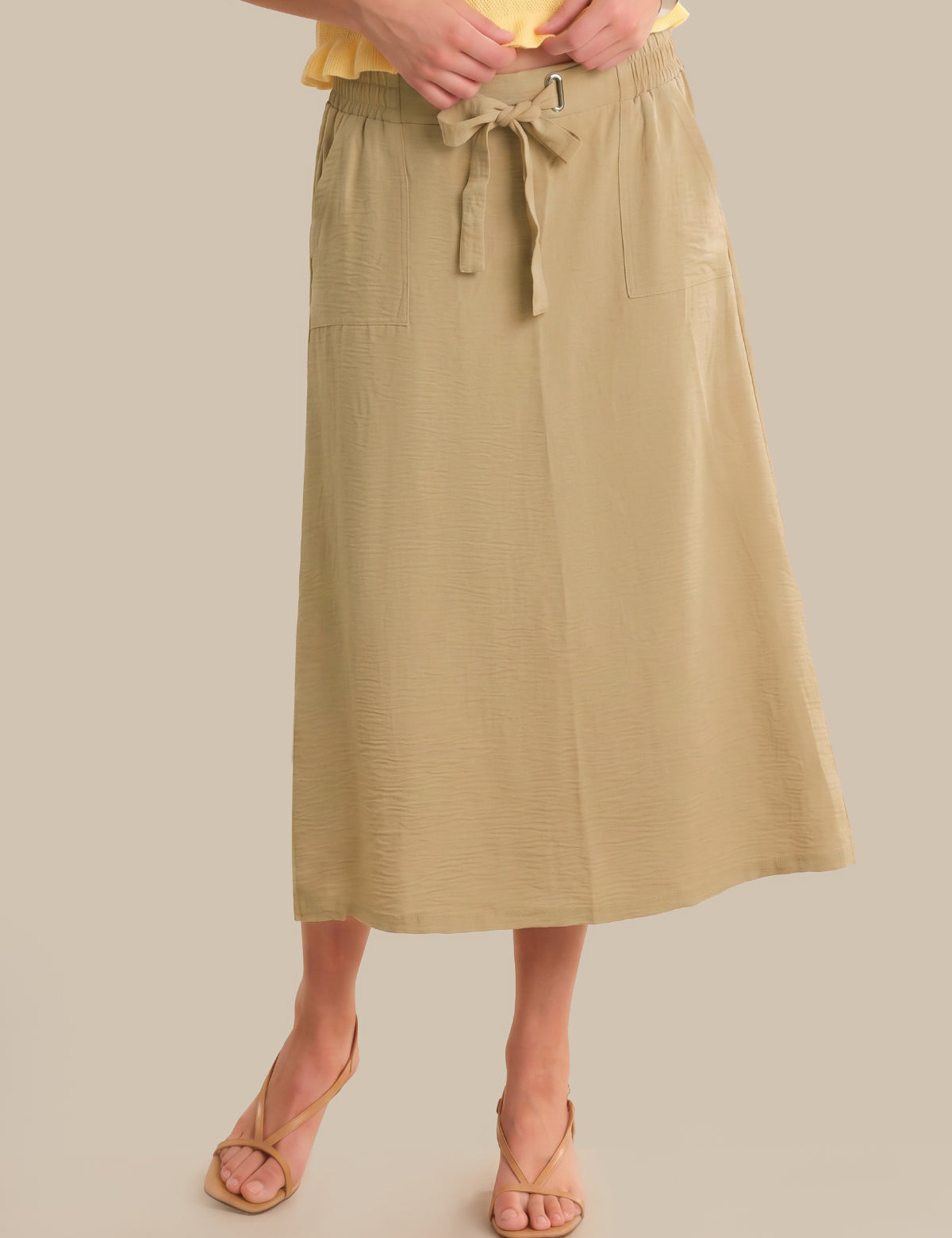 Person wearing a beige skirt with a plain background