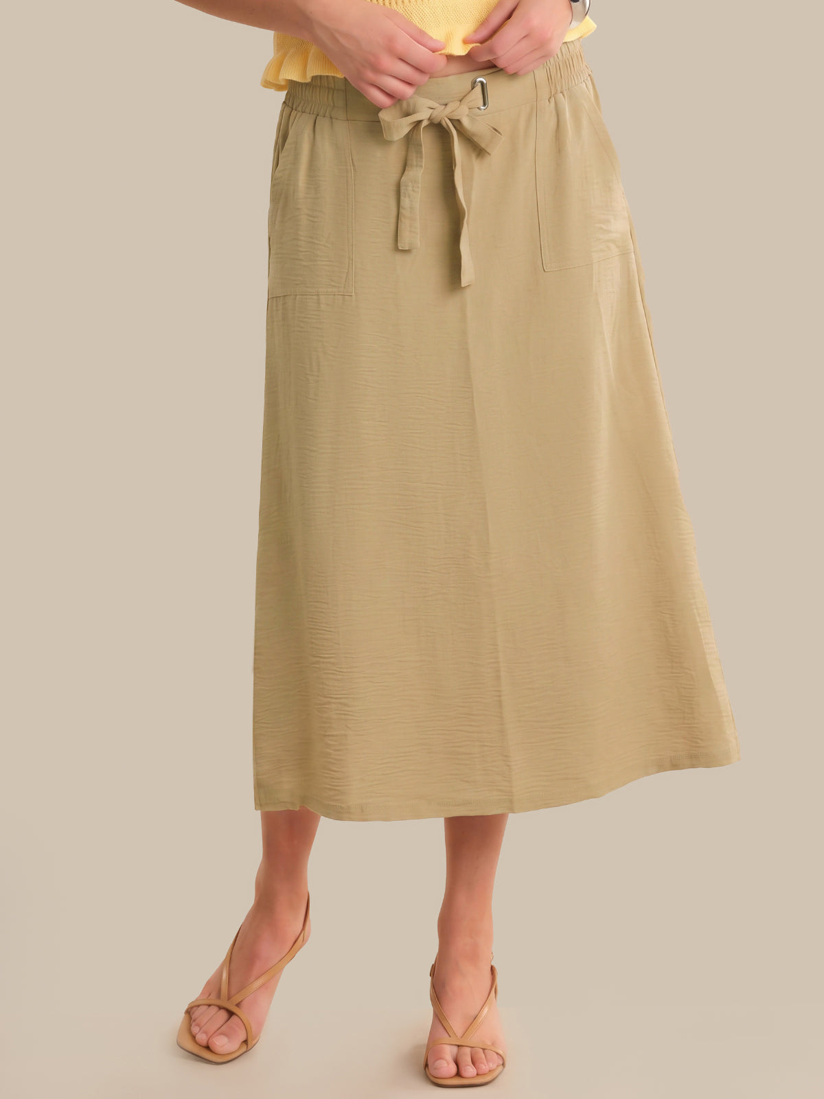 Person wearing a beige skirt with a plain background