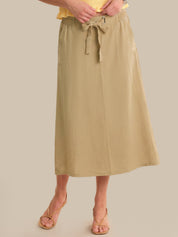 Person wearing a beige skirt with a plain background