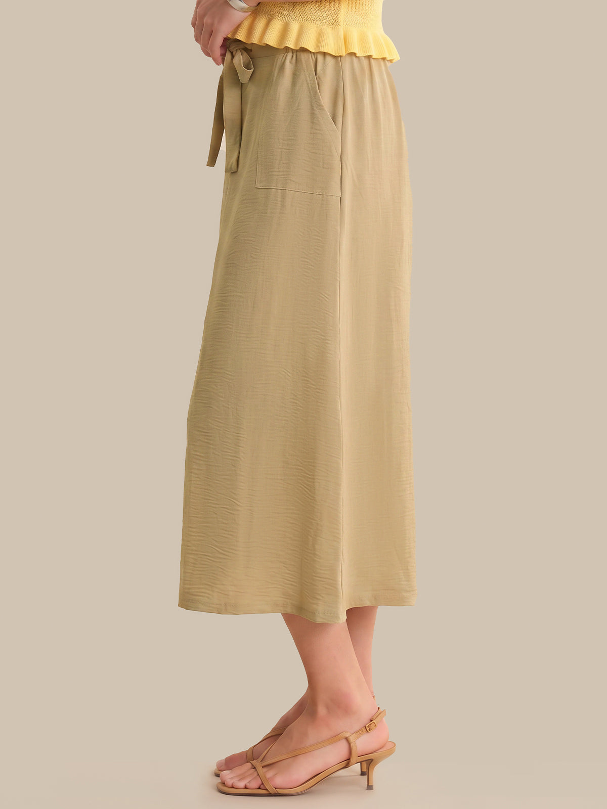Beige skirt worn by a person on a plain background