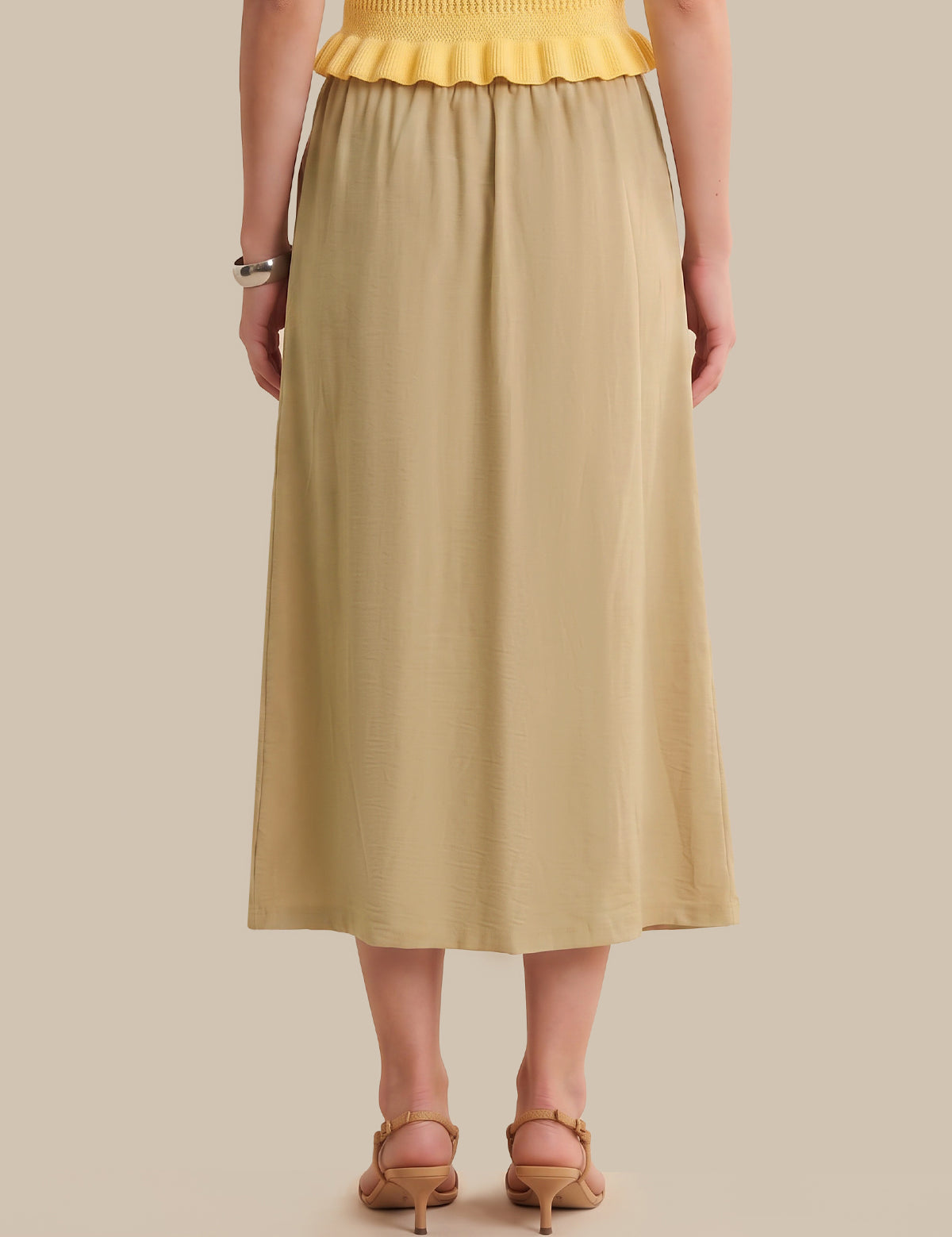 Person wearing a yellow top and beige skirt on a beige background