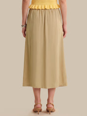 Person wearing a yellow top and beige skirt on a beige background