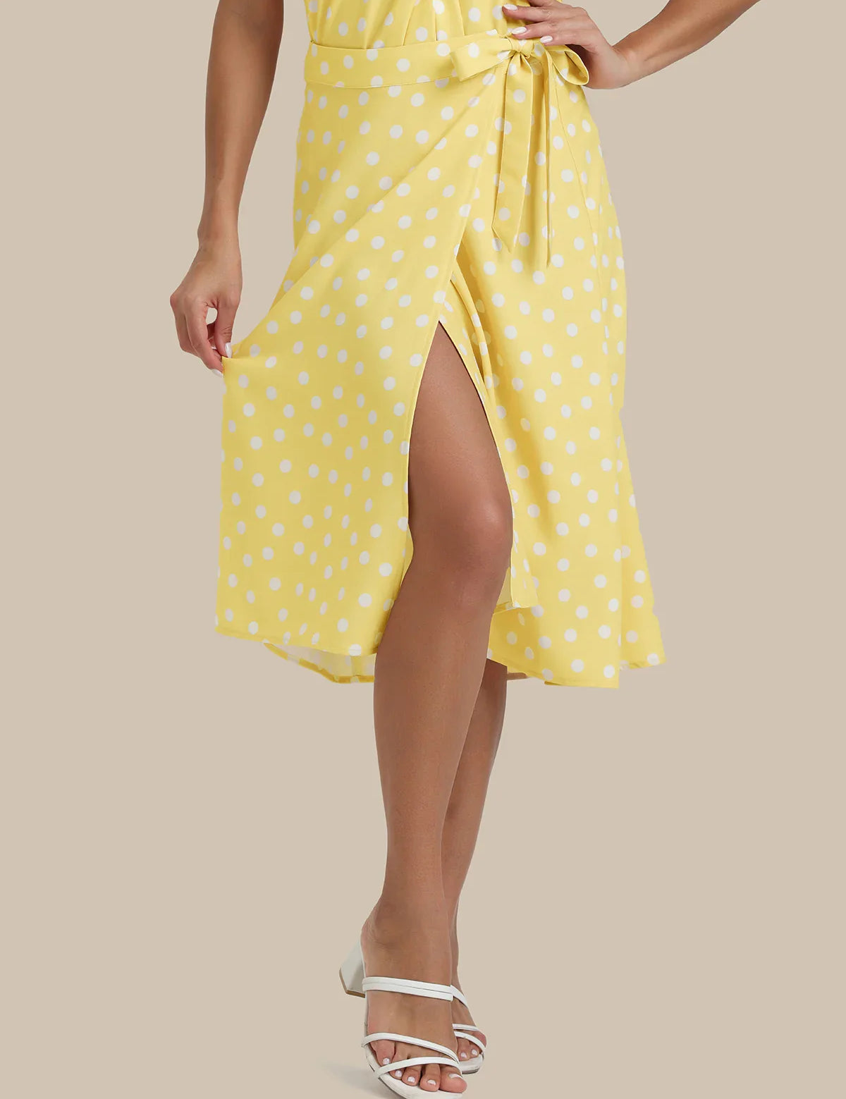 Woman wearing a yellow polka dot dress on a beige background