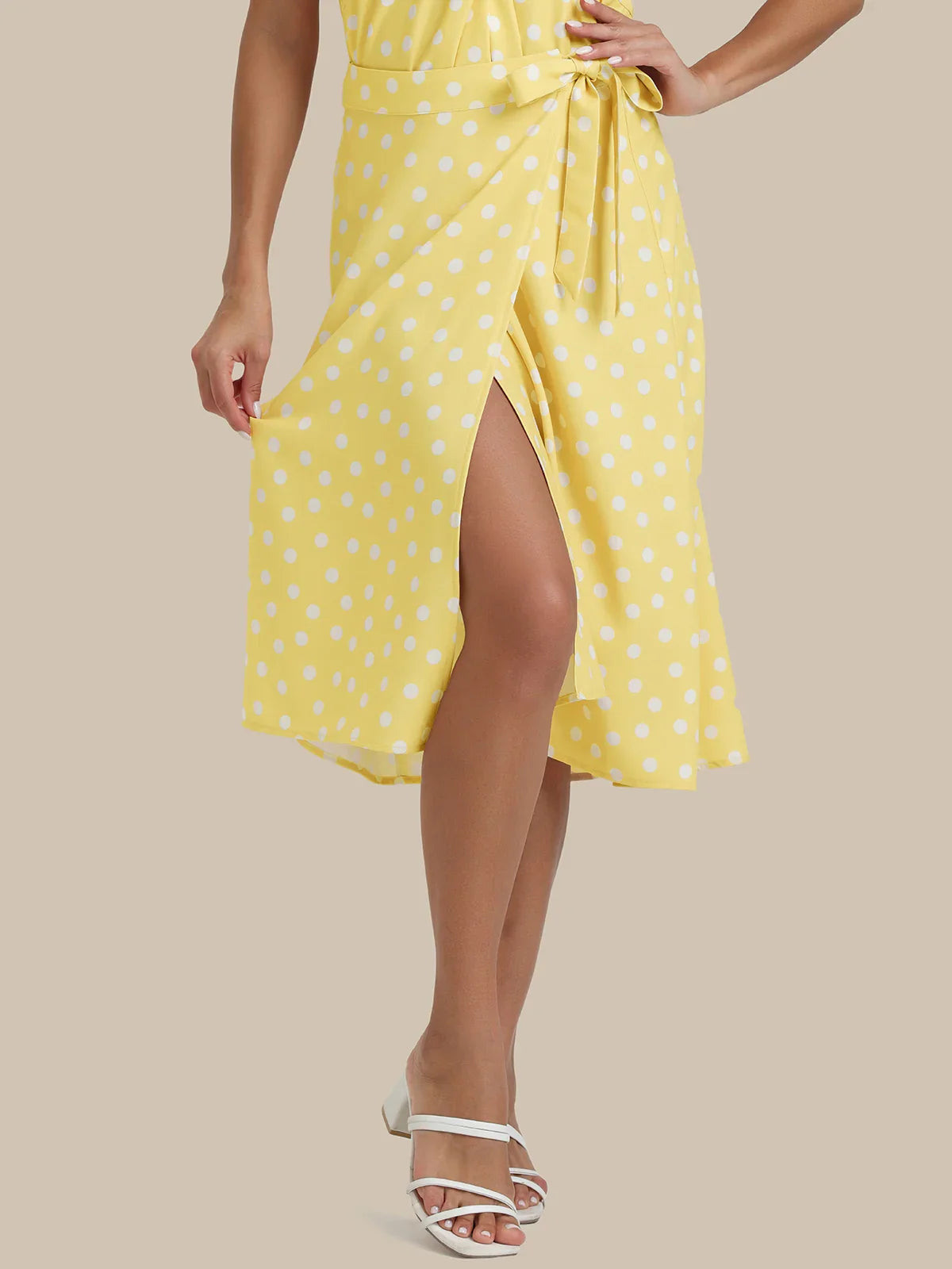 Woman wearing a yellow polka dot dress on a beige background