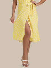 Woman wearing a yellow polka dot dress on a beige background