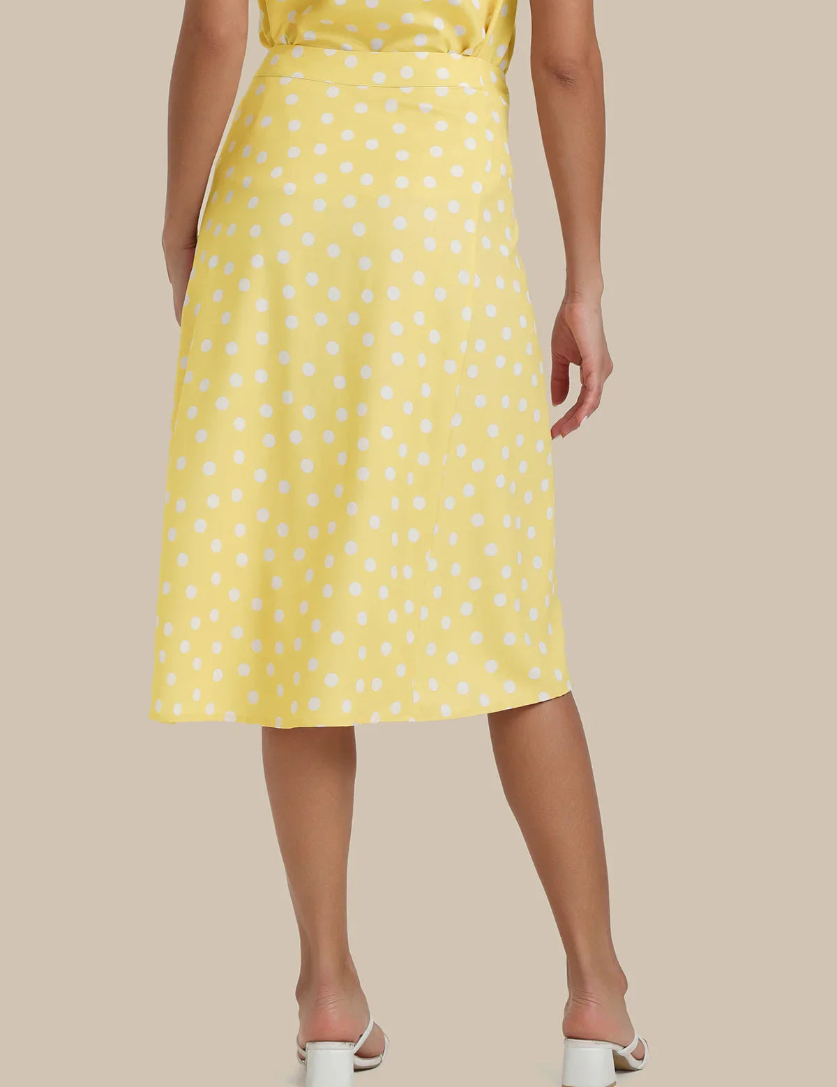 Yellow polka dot dress worn by a person on a beige background