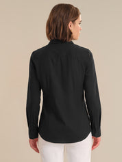 Woman wearing a black long-sleeve shirt against a beige background