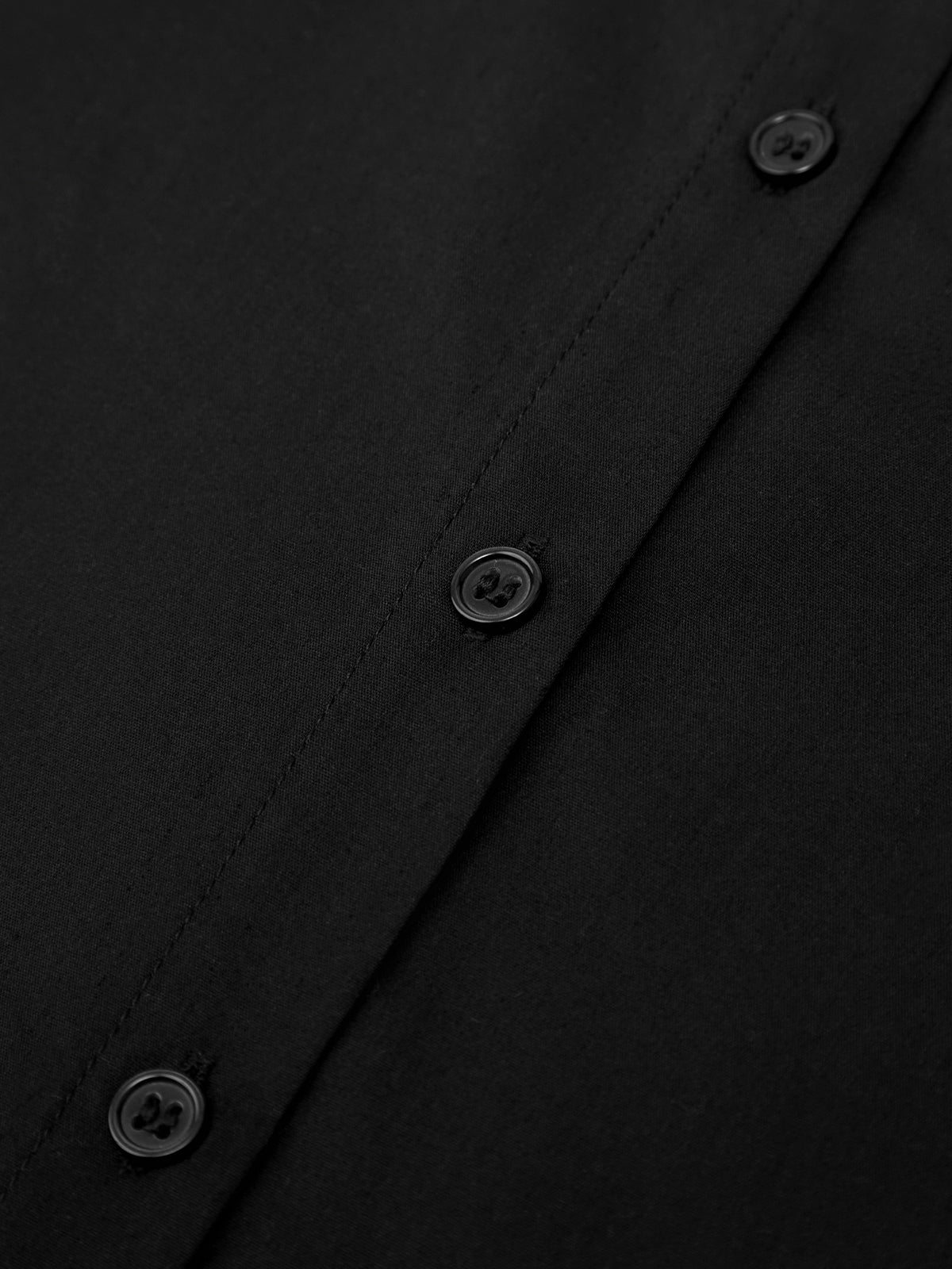 Close-up of a black shirt with buttons on a dark background