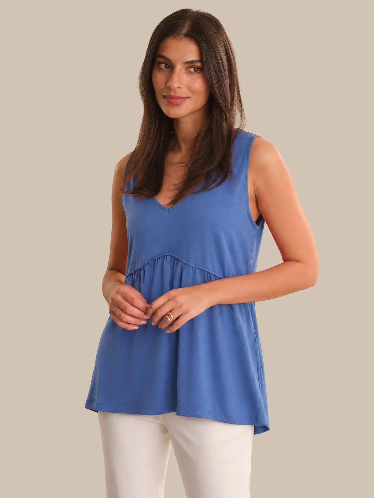 Woman wearing a blue sleeveless top against a beige background