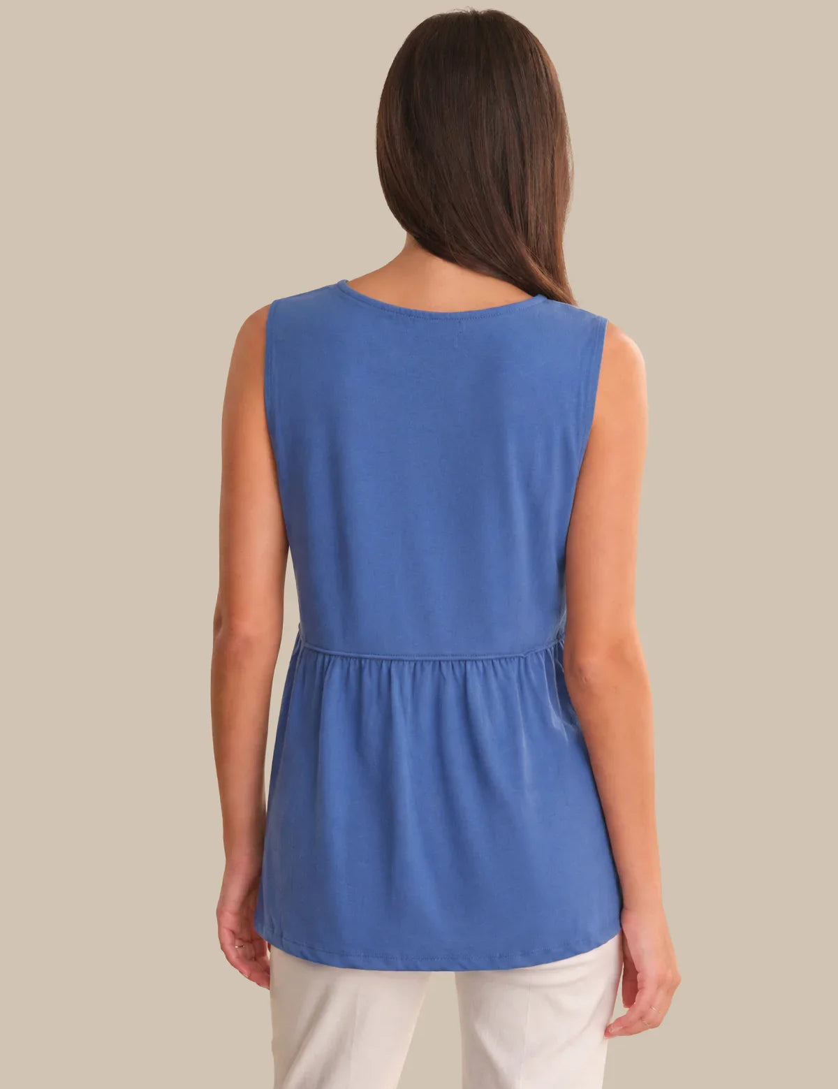 Woman wearing a blue sleeveless top against a beige background