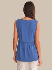 Woman wearing a blue sleeveless top against a beige background