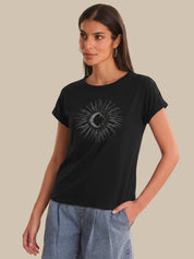 Woman wearing a black t-shirt with a sun and moon design on a beige background
