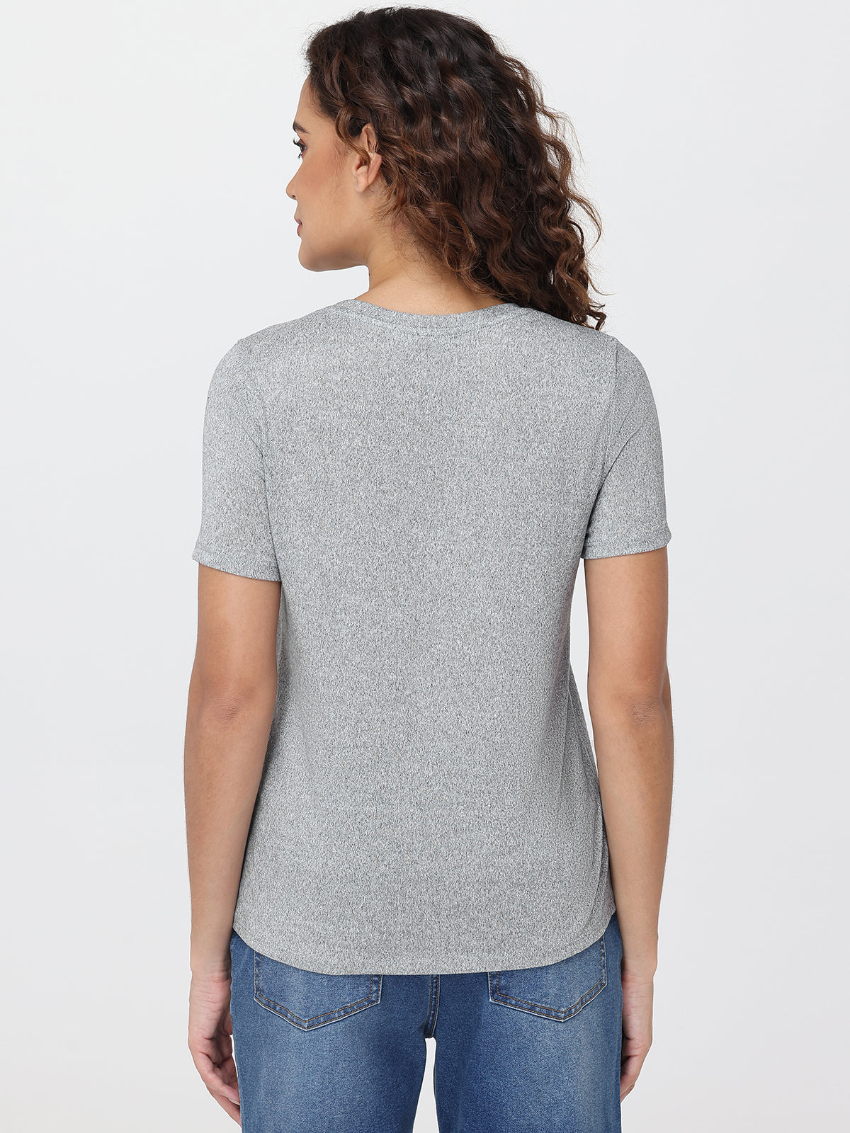 Woman wearing a gray t-shirt and blue jeans on a white background
