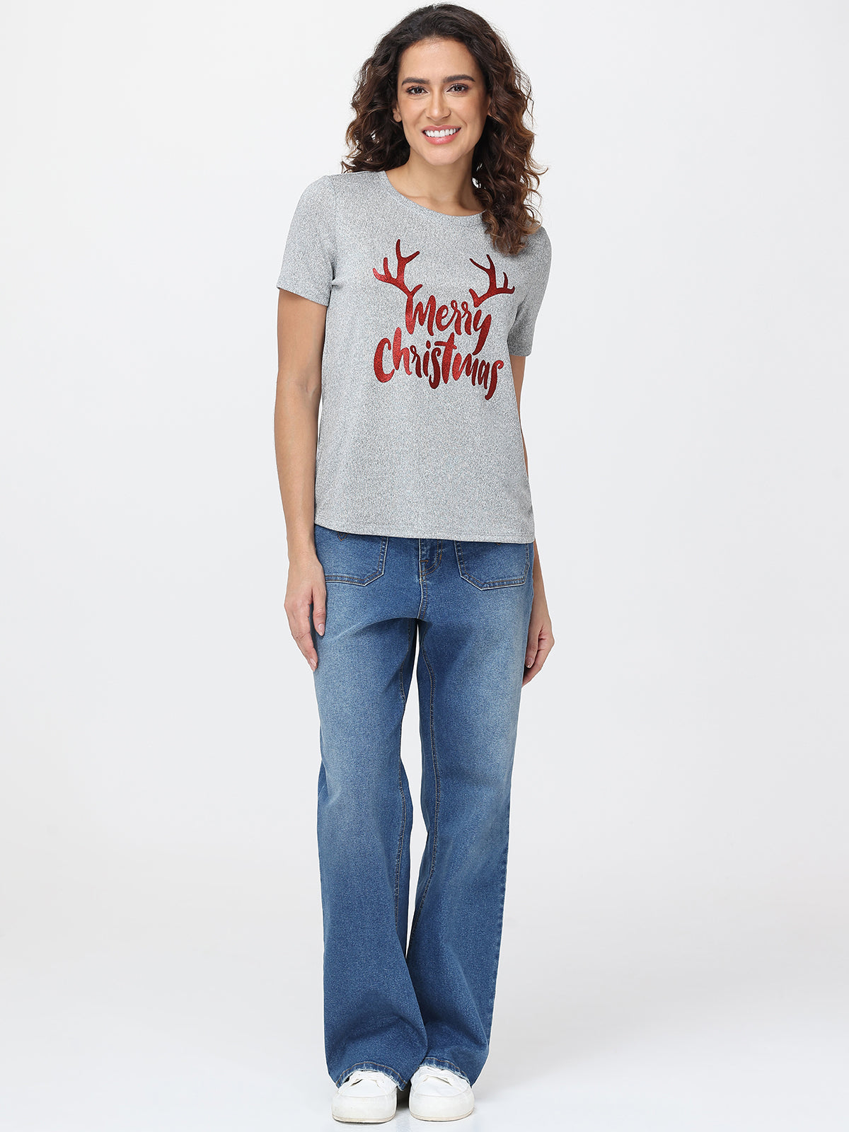 Woman wearing a gray t-shirt with 'Merry Christmas' text and blue jeans on a white background