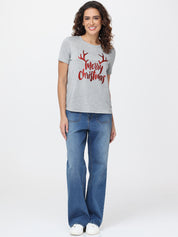 Woman wearing a gray t-shirt with 'Merry Christmas' text and blue jeans on a white background