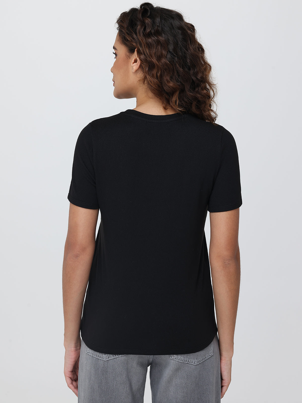 Person wearing a black t-shirt on a plain background