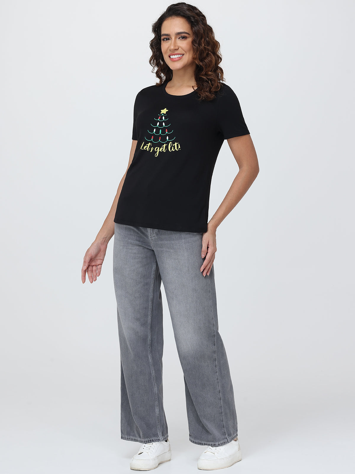 Woman wearing a black t-shirt with a graphic design and text, standing against a white background