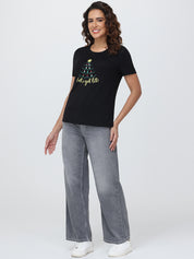 Woman wearing a black t-shirt with a graphic design and text, standing against a white background